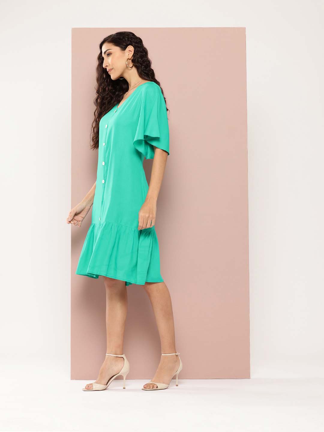 Solid rayon A-line style with a V-neckline and ruffle details. It features decorative show buttons